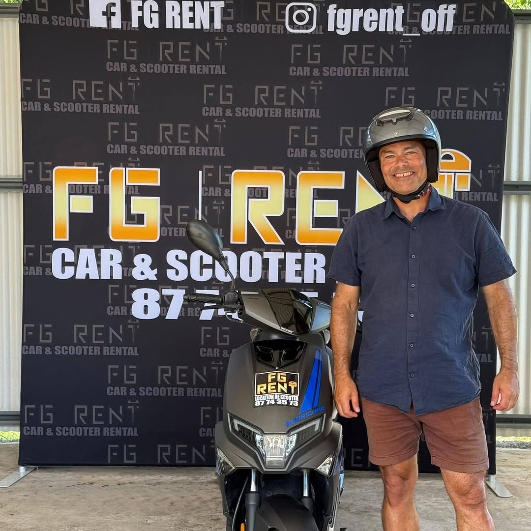 Client souriant avec son casque devant le mur FG Rent, à côté de son scooter